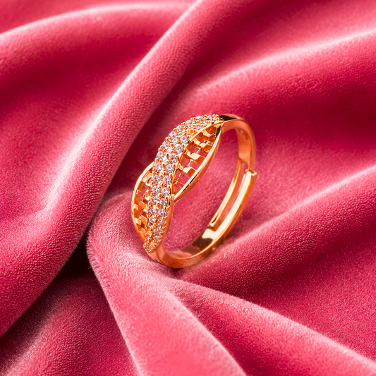 A rose gold ring with pavé-set clear stones, resting on draped dusty pink velvet fabric.