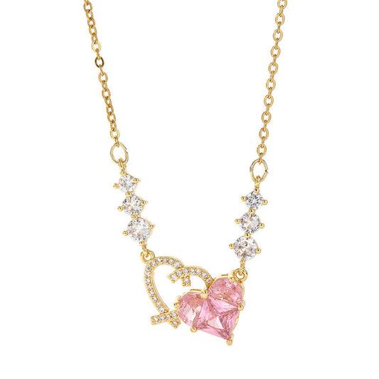 Gold necklace with a pink heart-shaped gemstone on a white background