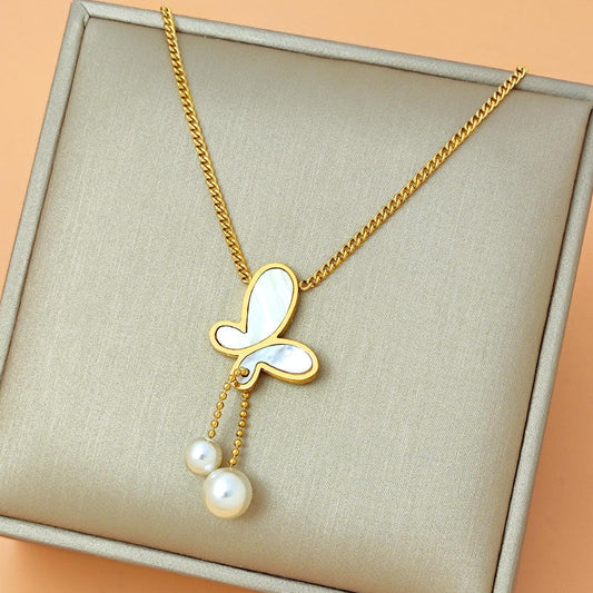 Gold necklace with a butterfly pendant and pearls on a beige fabric background