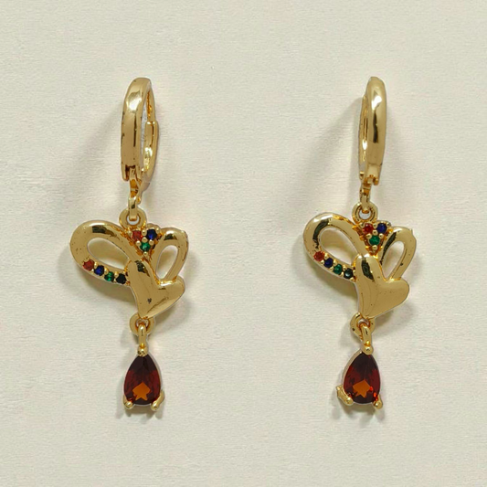 Gold earrings with heart designs and red gemstones on a light gray background