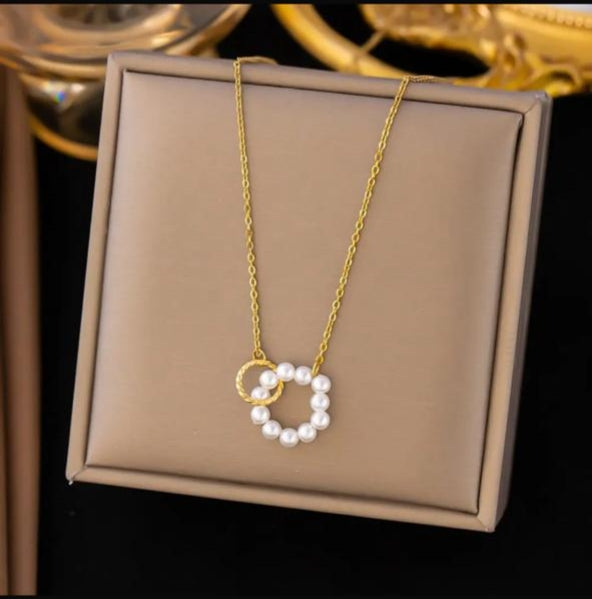 Gold necklace with pearl pendant on a beige display box