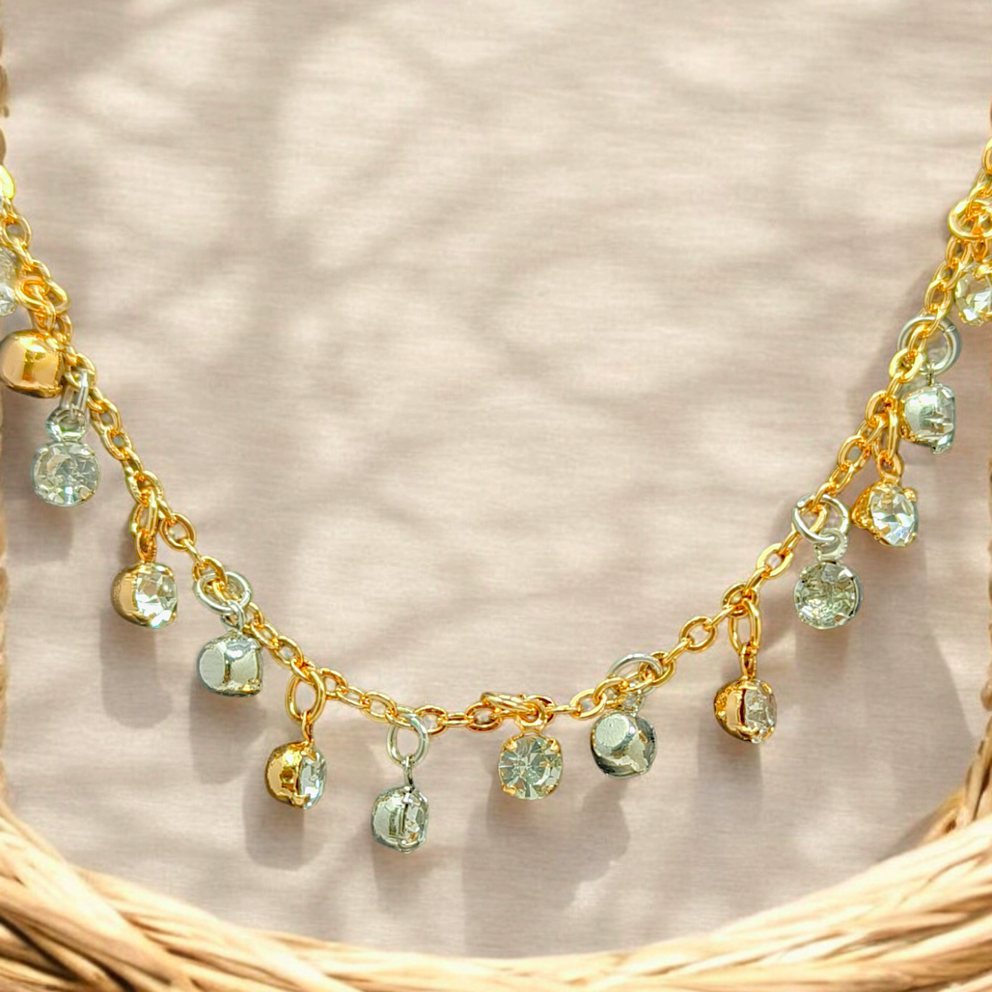 Gold necklace with green gemstones on a textured beige background