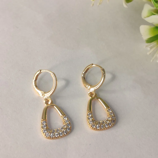 Gold earrings with clear stones on a light background