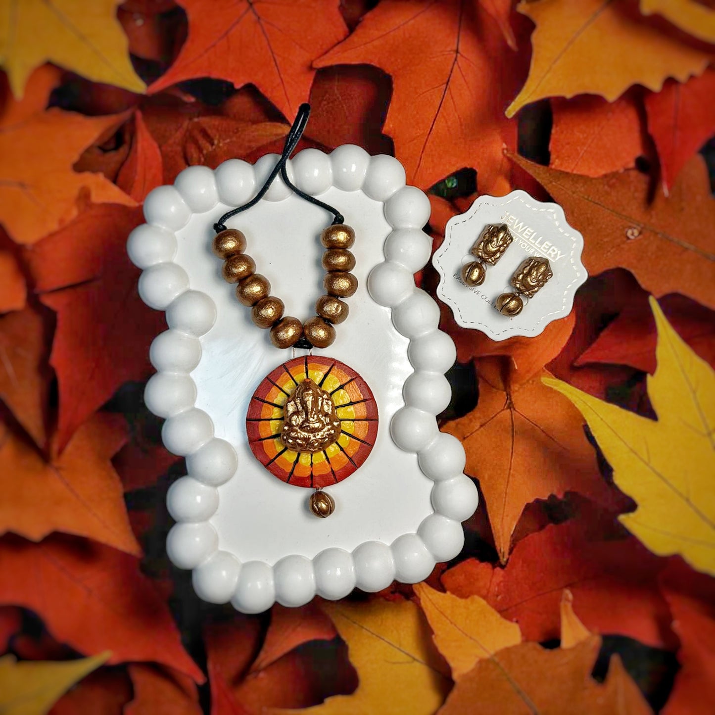 Handmade Jewelry Ganesha Necklace And Earring set with brown beads on autumn leaves background
