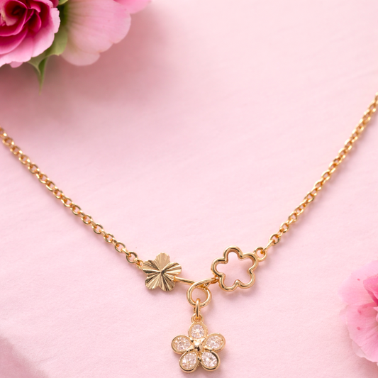 Gold necklace with floral pendants on a pink background