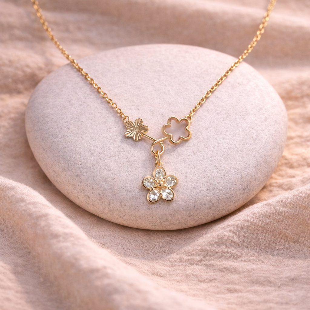 Gold necklace with floral pendants on a stone surface