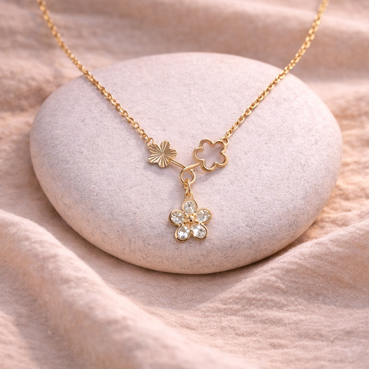 Gold necklace with floral pendants on a stone surface