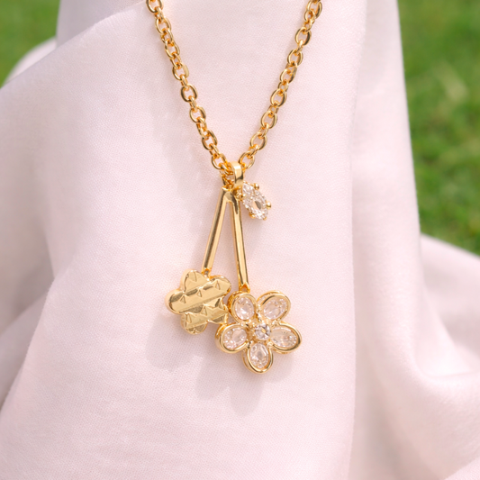Gold necklace with floral pendant on a white fabric background