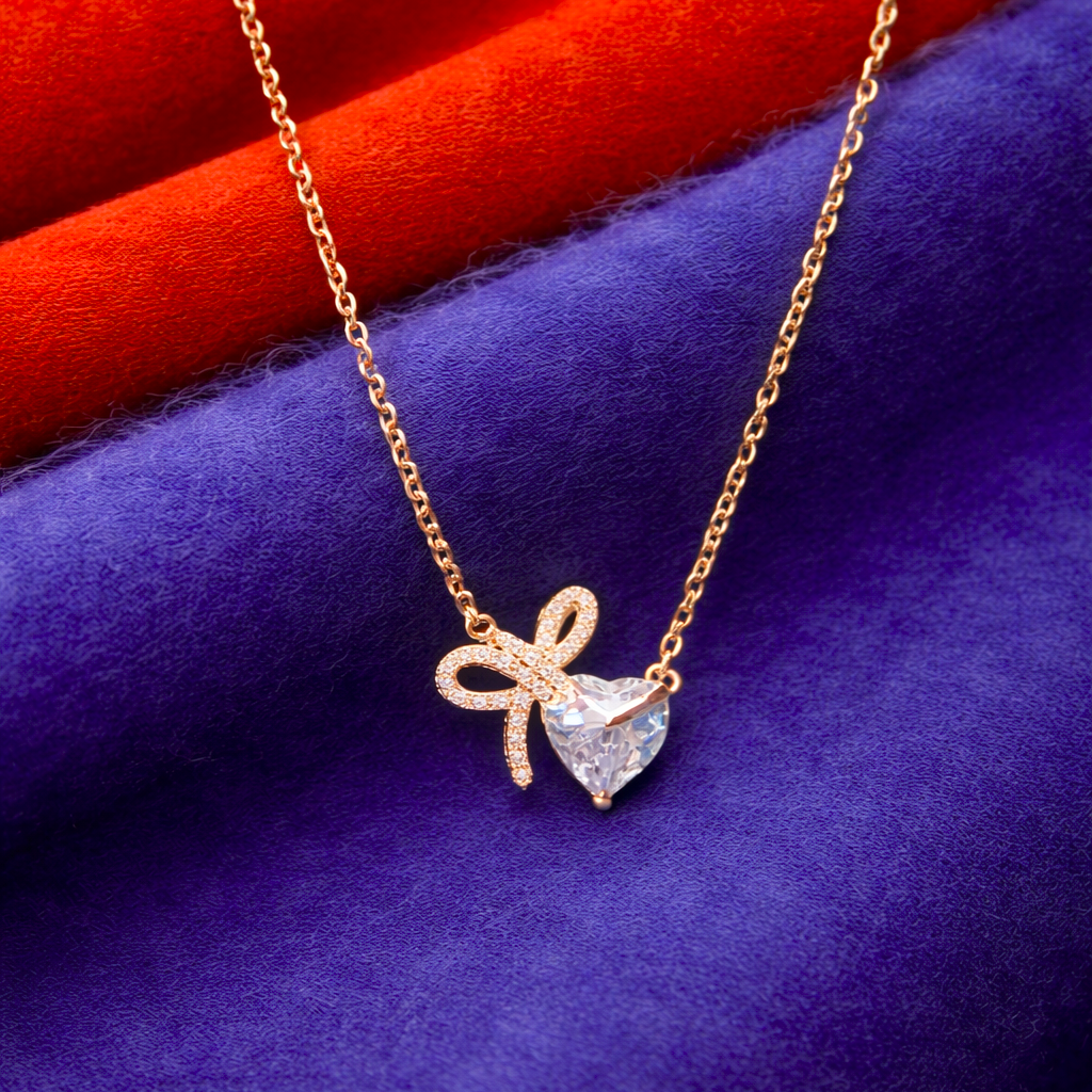 Gold necklace with a heart-shaped pendant on a blue and red fabric background