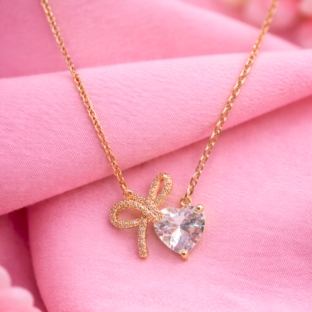 Gold necklace with a heart-shaped pendant on pink fabric