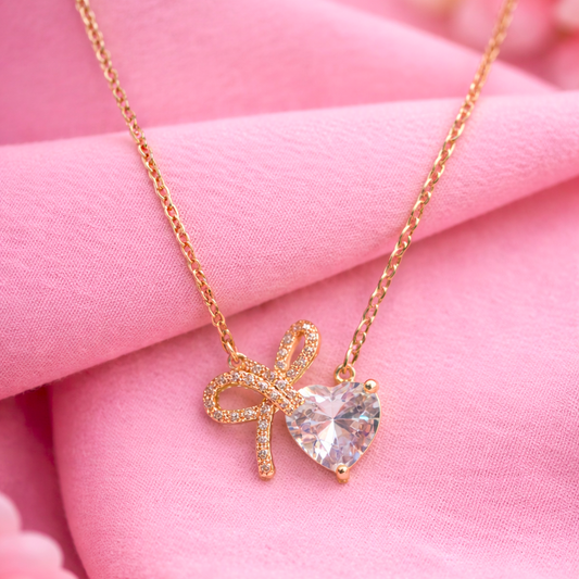 Gold necklace with a heart-shaped pendant on pink fabric
