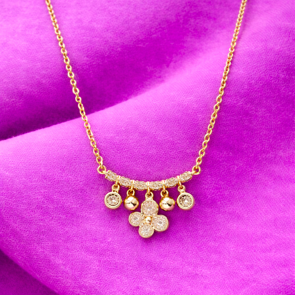 Gold necklace with floral pendant on a purple fabric background