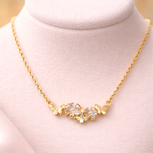 Gold necklace with floral design on a mannequin bust against a light pink background