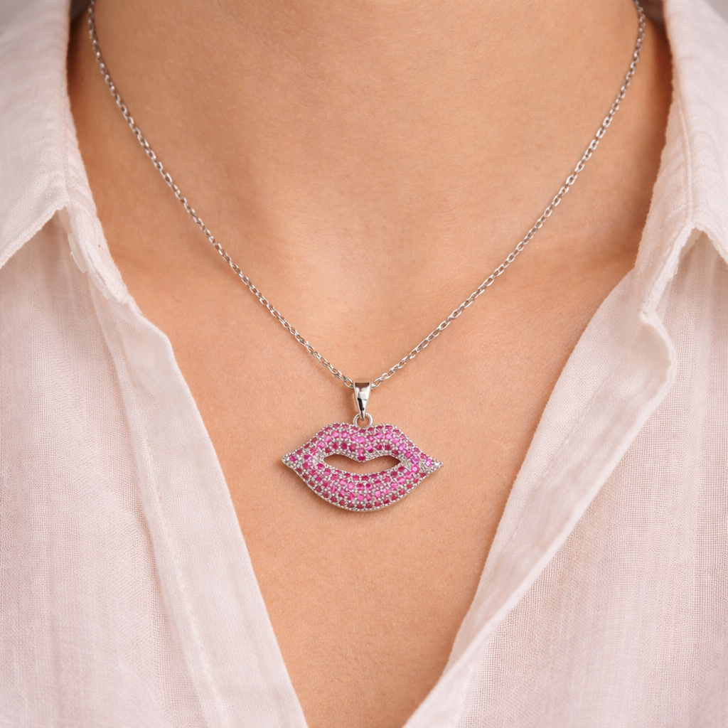 Necklace with a pink lip-shaped pendant worn by a person in a white shirt.