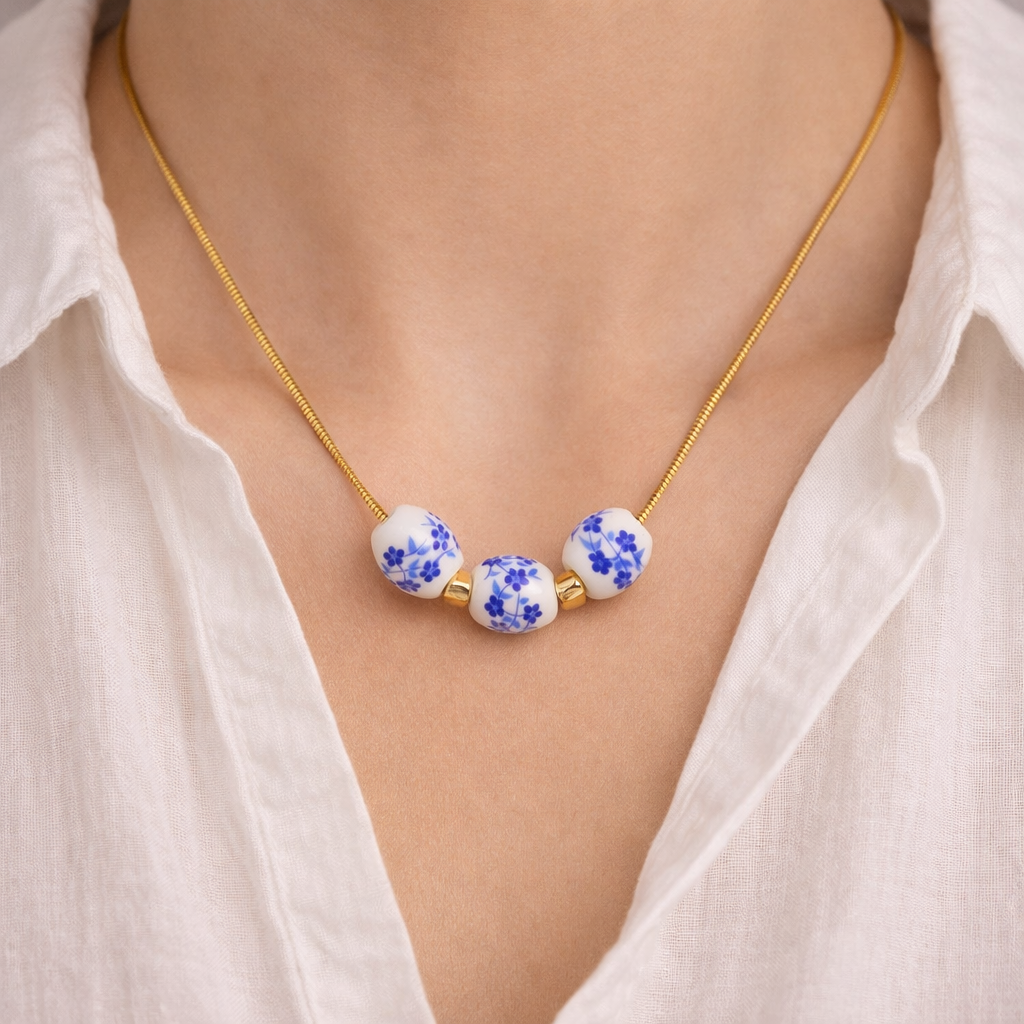 Necklace with blue floral beads worn by a person in a white shirt