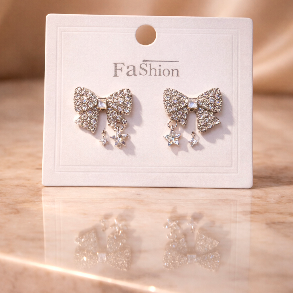 Bow-shaped earrings on a 'Fa$ion' branded card against a beige background