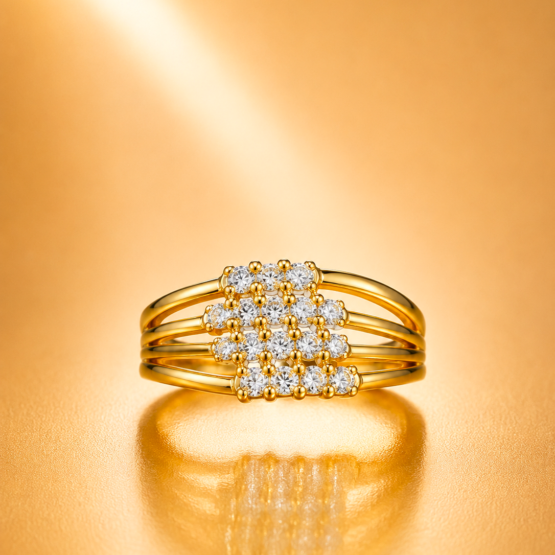 A gold ring with a square cluster of clear gemstones in the center, photographed on a warm gold reflective surface.