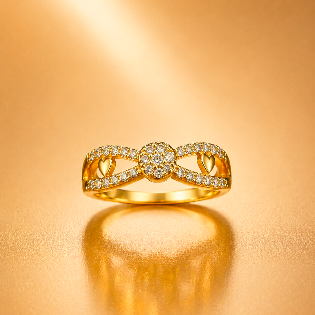 A gold ring with a bow-like openwork design, set with small clear stones, displayed on a warm gold reflective surface.