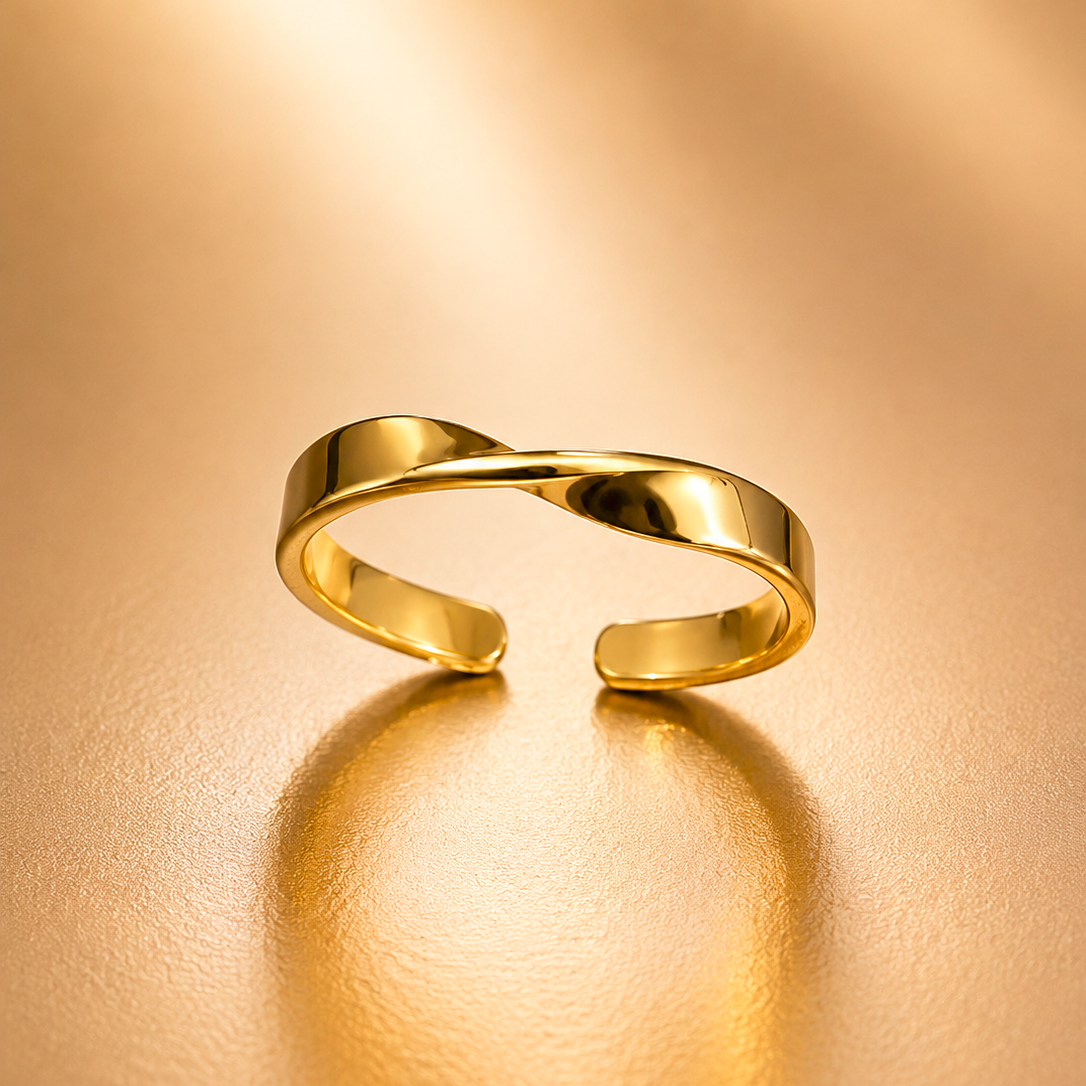 A polished gold open ring with a twisted, intertwined band design, resting on a warm, textured gold surface with a soft reflection.