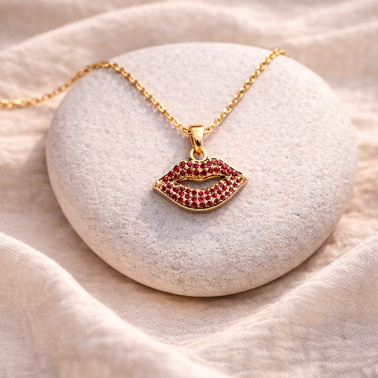 Gold necklace with a lip-shaped pendant on a stone surface