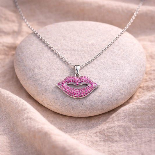 Necklace with a pink lip-shaped pendant on a stone surface