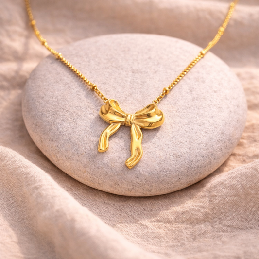 Gold bow-shaped necklace on a stone surface
