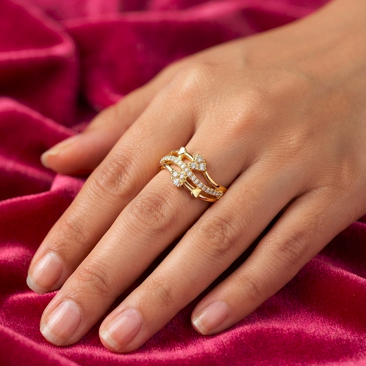 A close-up of a hand wearing a delicate gold ring set with small clear stones, resting on a rich magenta velvet fabric background.