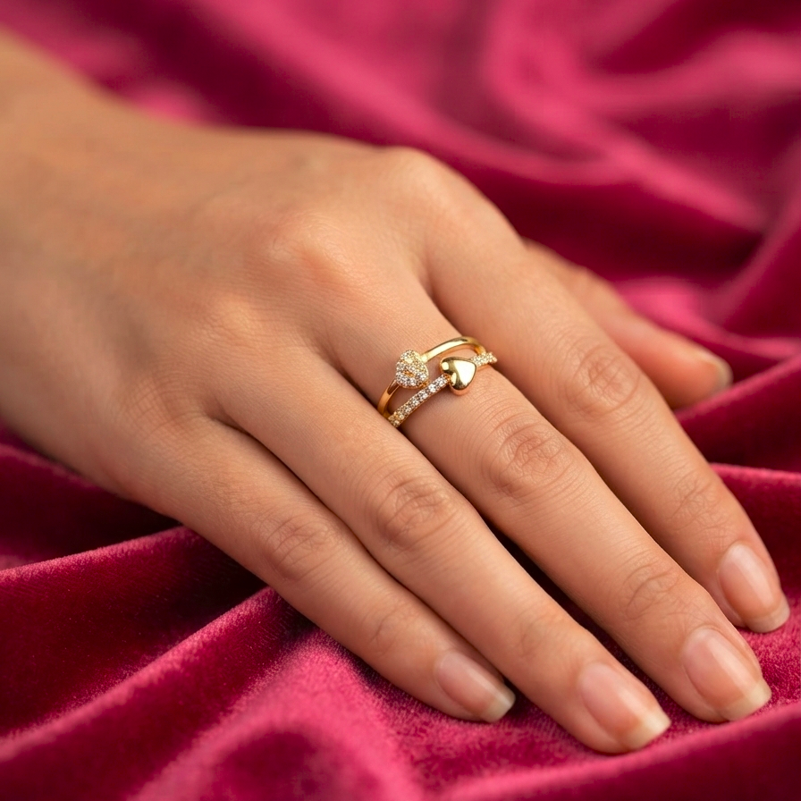 A close-up of a hand resting on draped burgundy velvet fabric, wearing a gold ring with a small clear gemstone cluster.