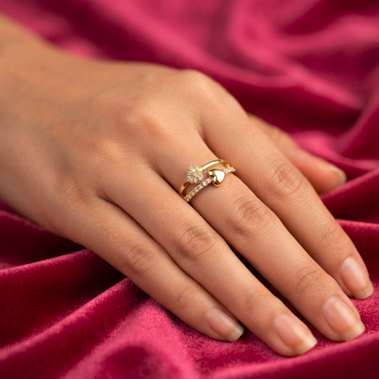 A close-up of a hand resting on draped burgundy velvet fabric, wearing a gold ring with a small clear gemstone cluster.