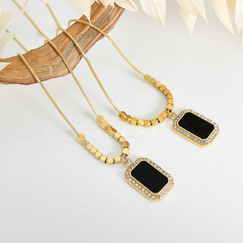 Gold necklaces with black pendants on a light background
