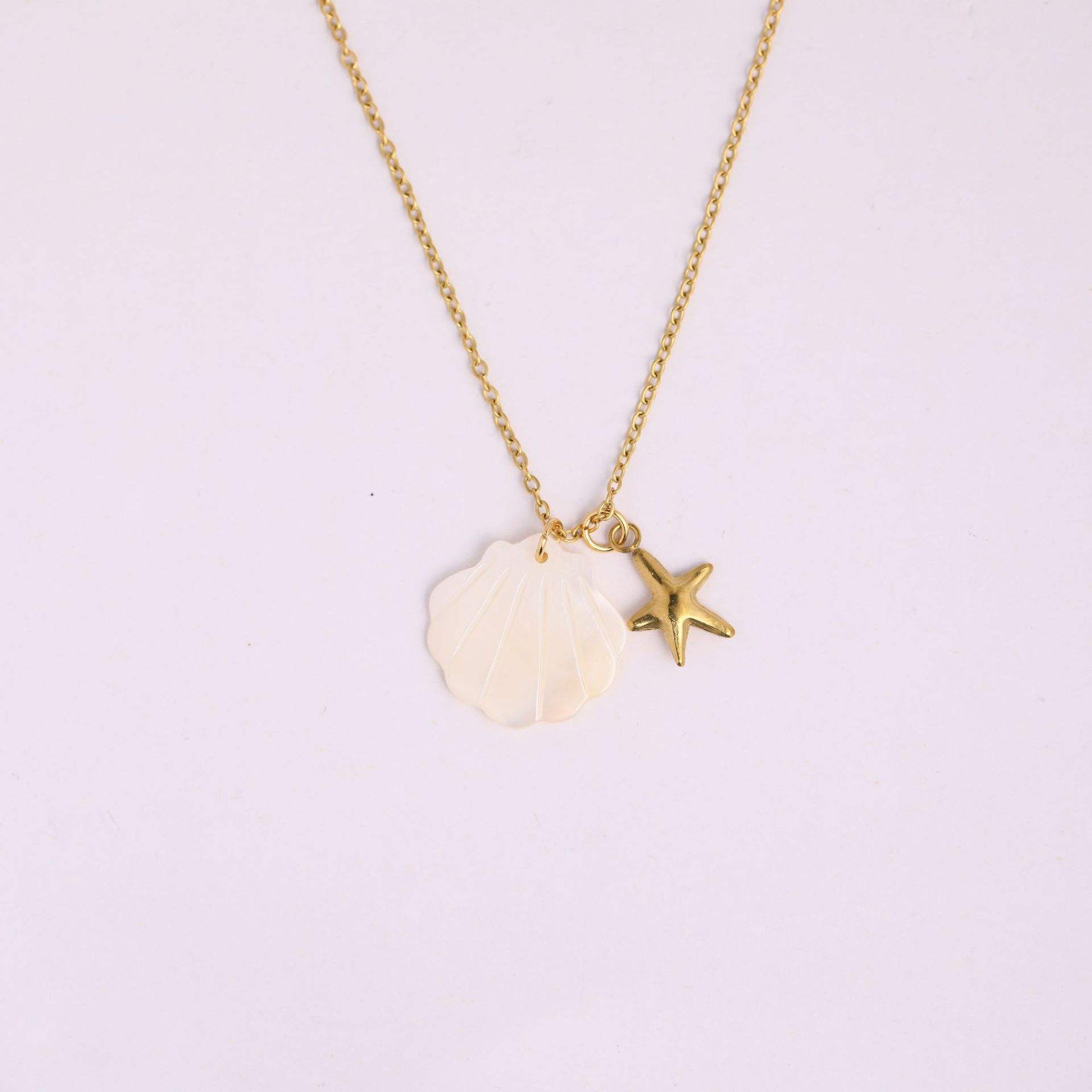 Necklace with a shell and starfish pendant on a light purple background