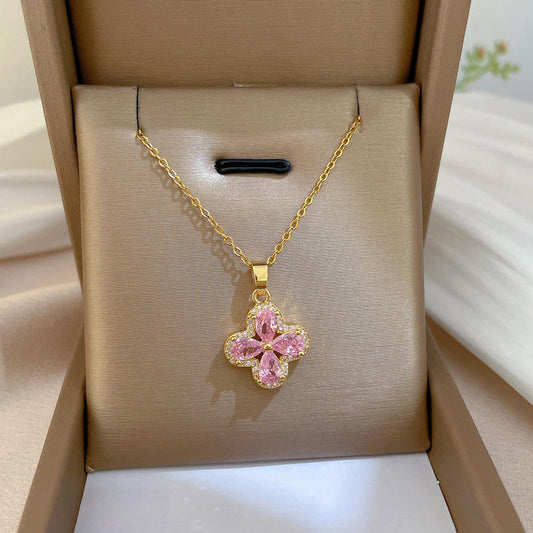 Gold necklace with a pink flower pendant in a beige jewelry box.