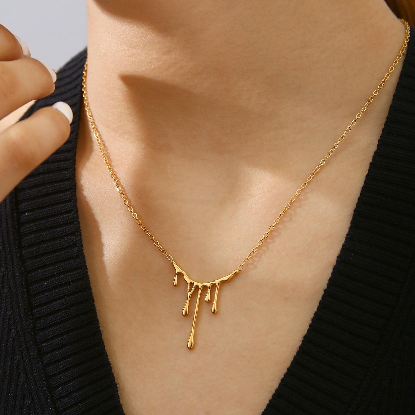 Gold necklace with a unique design worn by a person against a neutral background