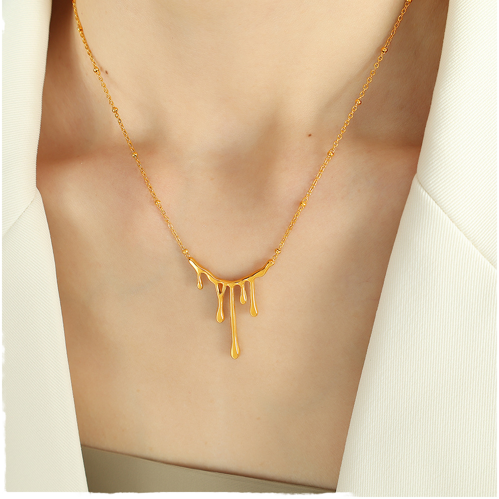 Gold necklace with a unique design on a person wearing a white top.