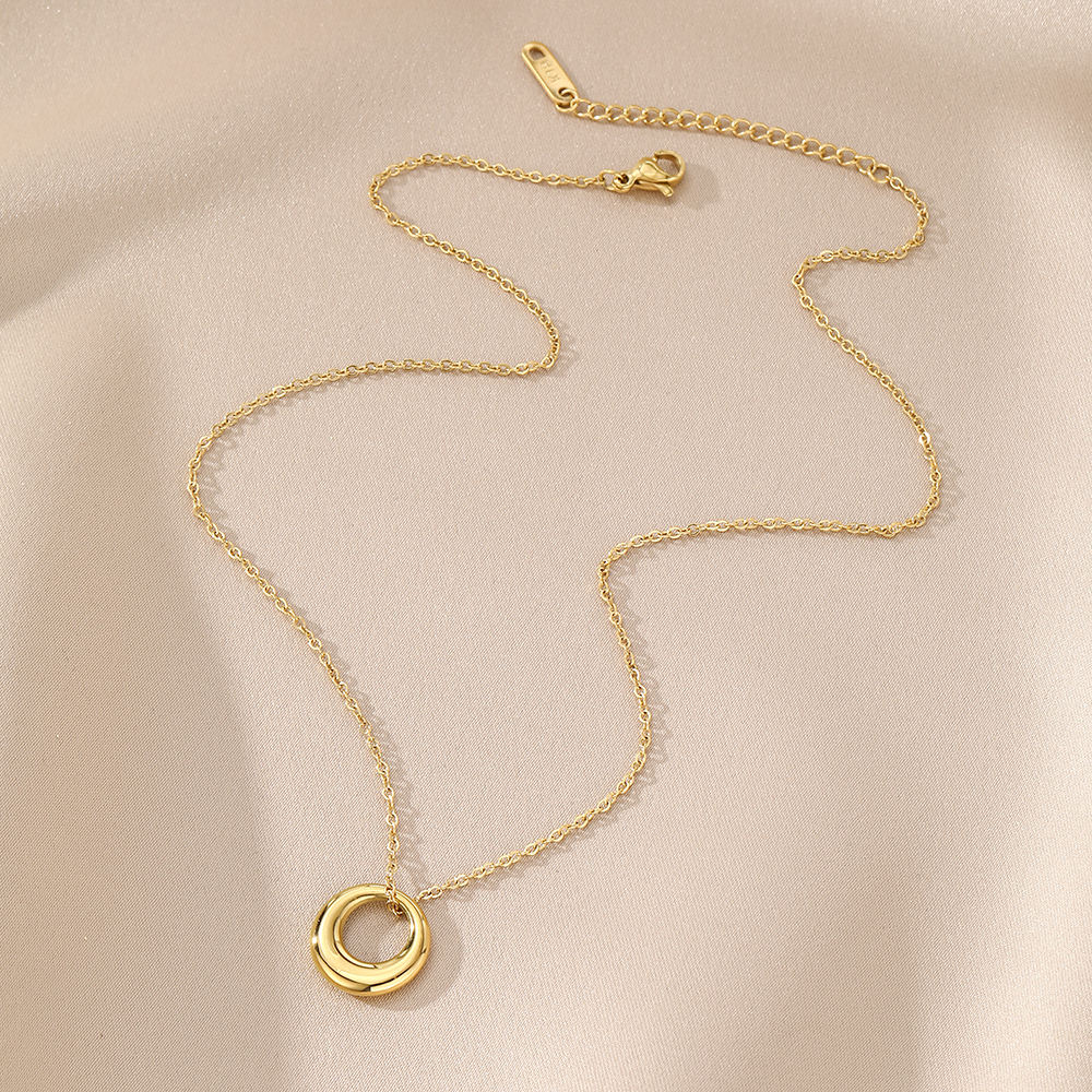 Gold necklace with a circular pendant on a beige background