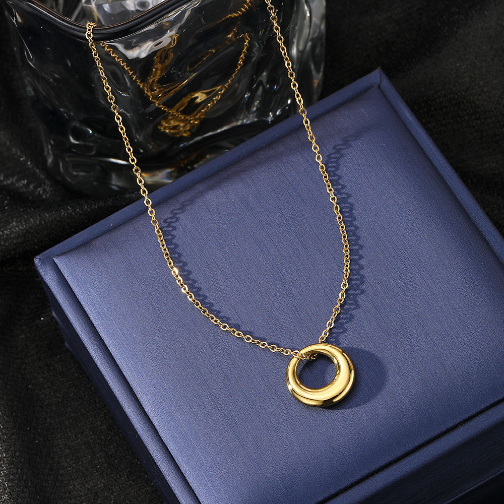 Gold necklace with a circular pendant on a blue box