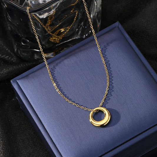 Gold necklace with a circular pendant on a blue box