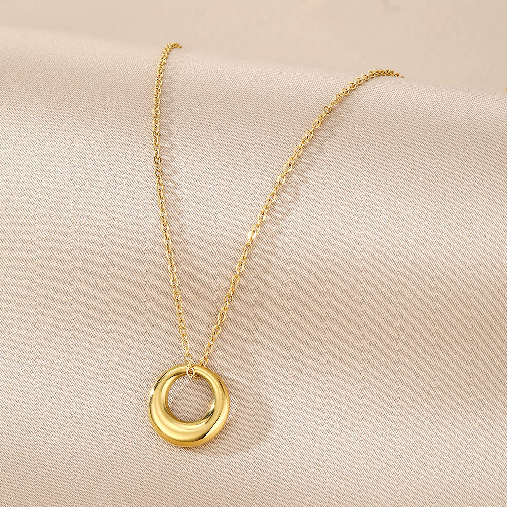 Gold necklace with a circular pendant on a beige fabric background