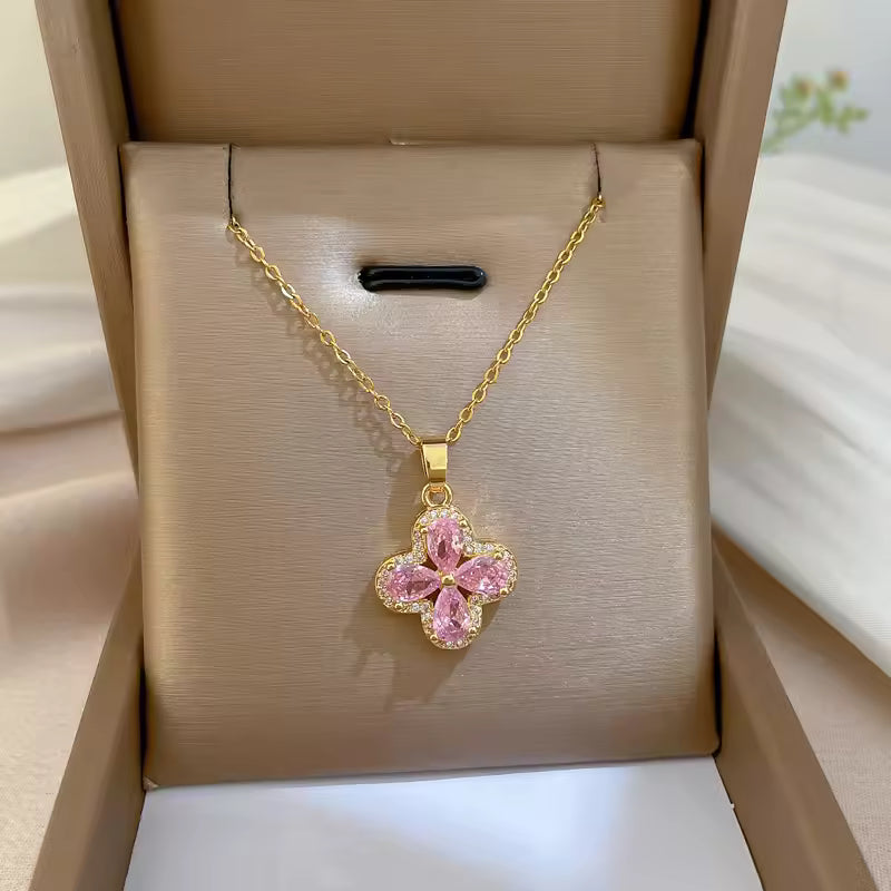 Gold necklace with a pink flower pendant in a beige jewelry box.