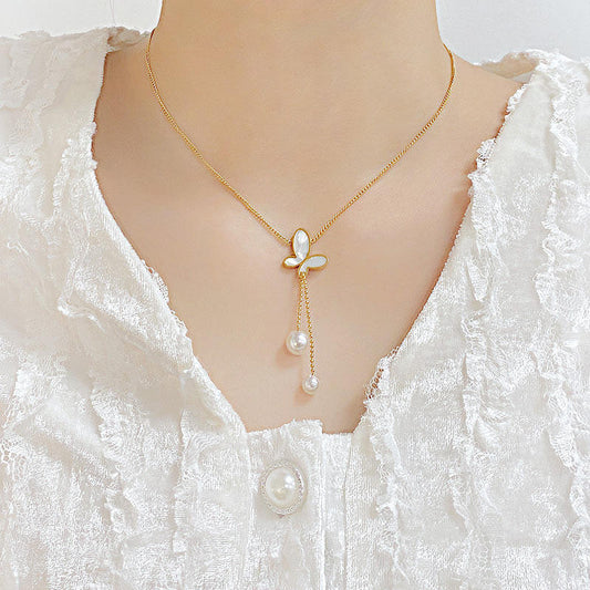 Gold necklace with pearl pendant on a mannequin wearing a white lace garment.