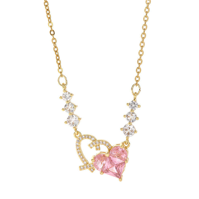 Gold necklace with a pink heart-shaped gemstone on a white background
