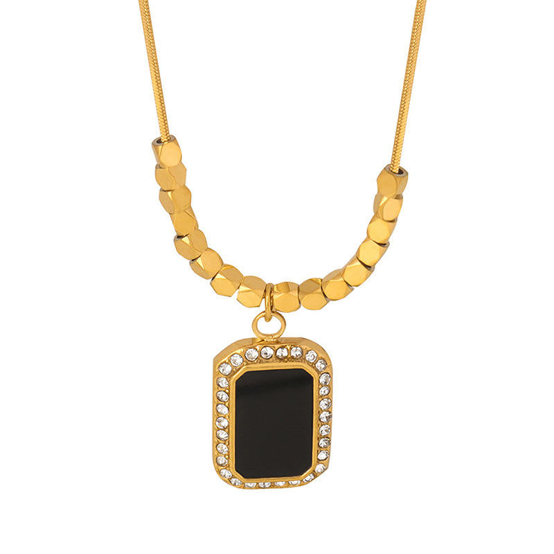 Gold necklace with a black pendant on a white background