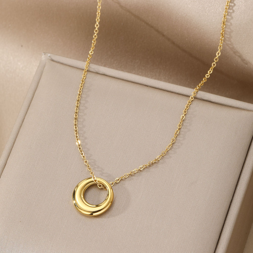 Gold necklace with a circular pendant on a beige background