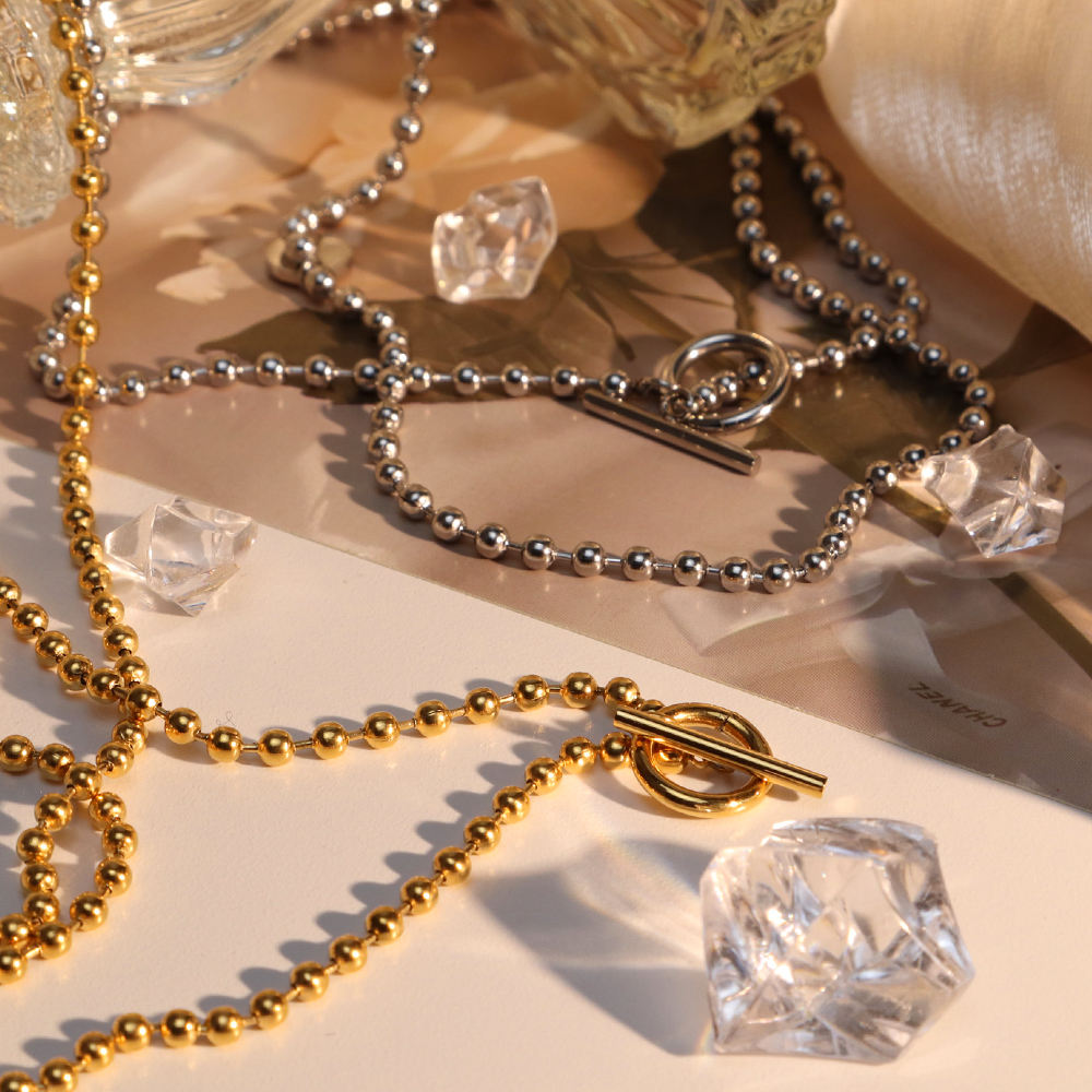 Gold and silver necklaces with clear crystal pendants on a soft surface