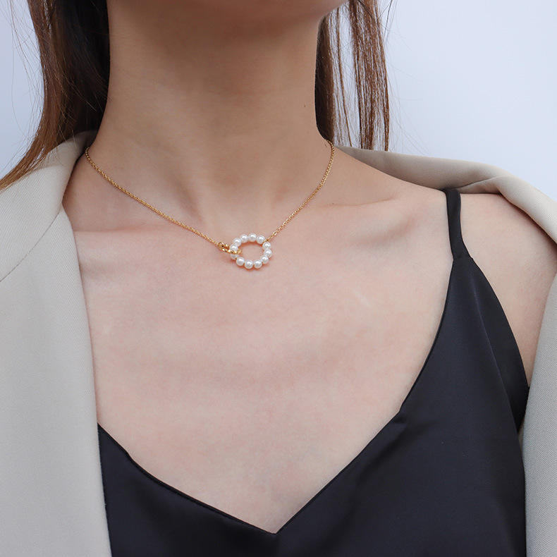 Necklace with a circular pendant worn by a person against a neutral background