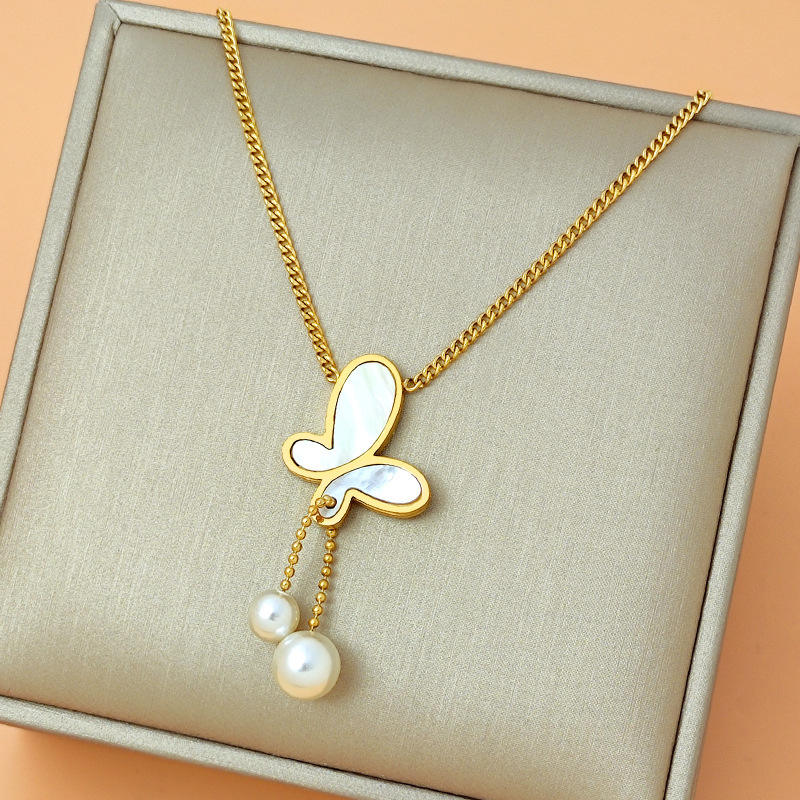 Gold necklace with a butterfly pendant and pearls on a beige fabric background