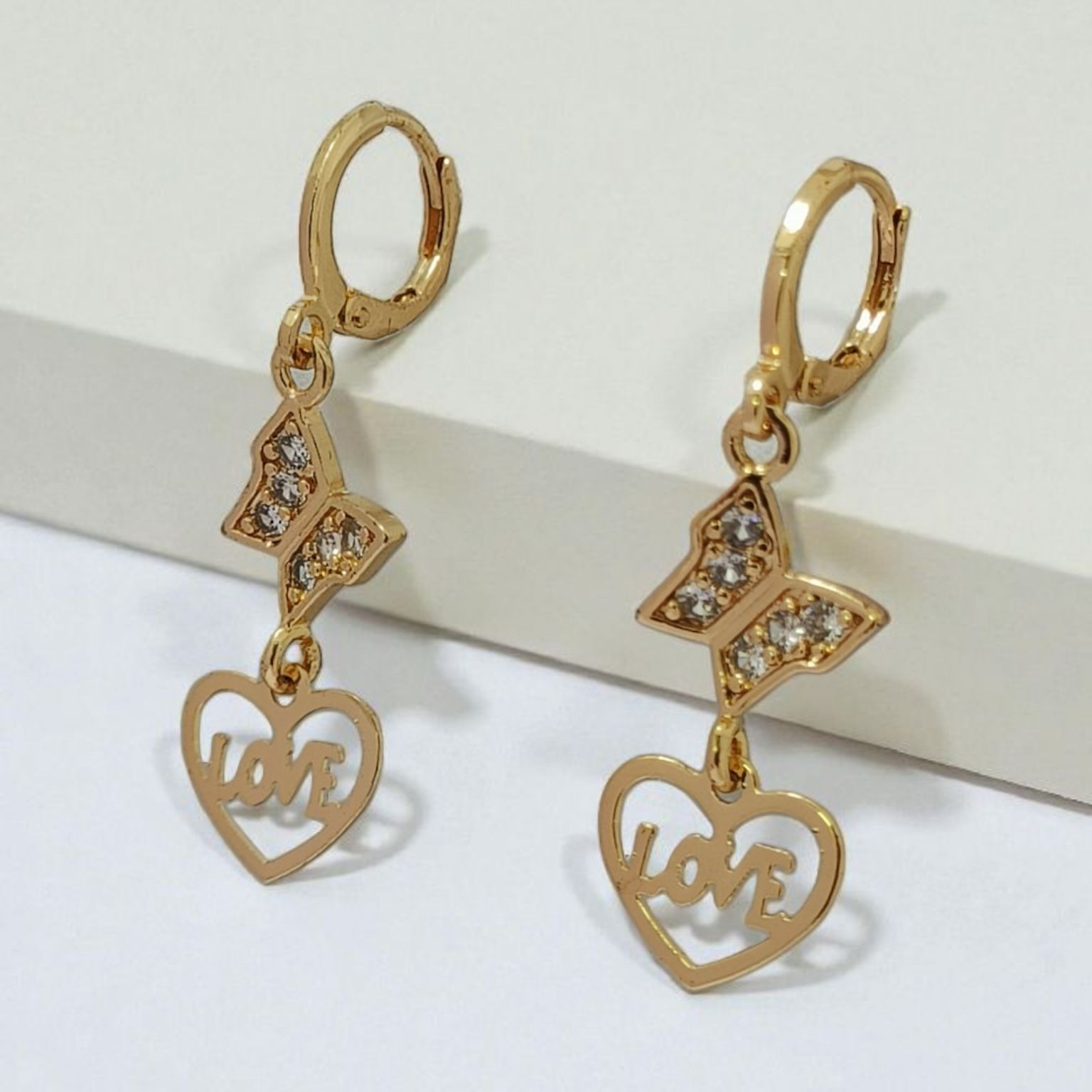 Gold heart-shaped earrings with 'LOVE' inscription on a white background