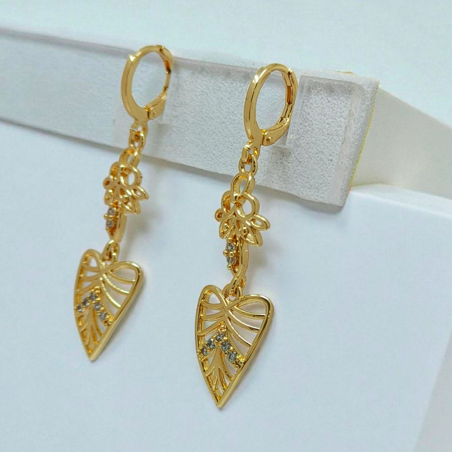 Gold leaf-shaped earrings on a white background