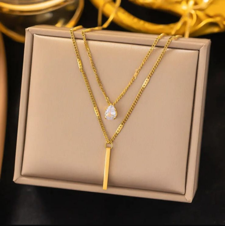 Gold necklace with a heart-shaped pendant on a beige jewelry box