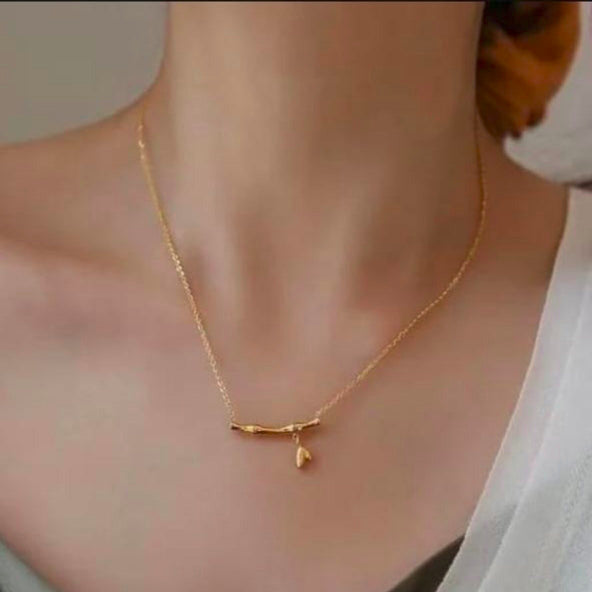 Gold necklace worn by a person with a neutral background